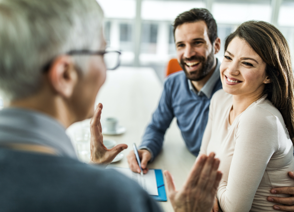 man and woman sitting at table taking notes and smiling