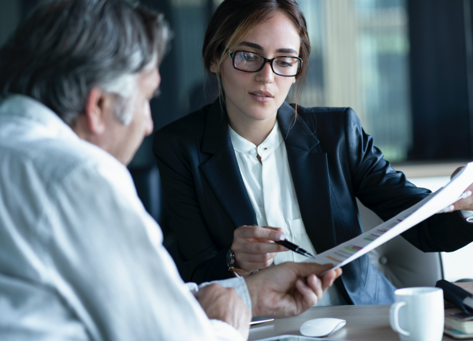 professional woman sitting at table pointing to paper with pen