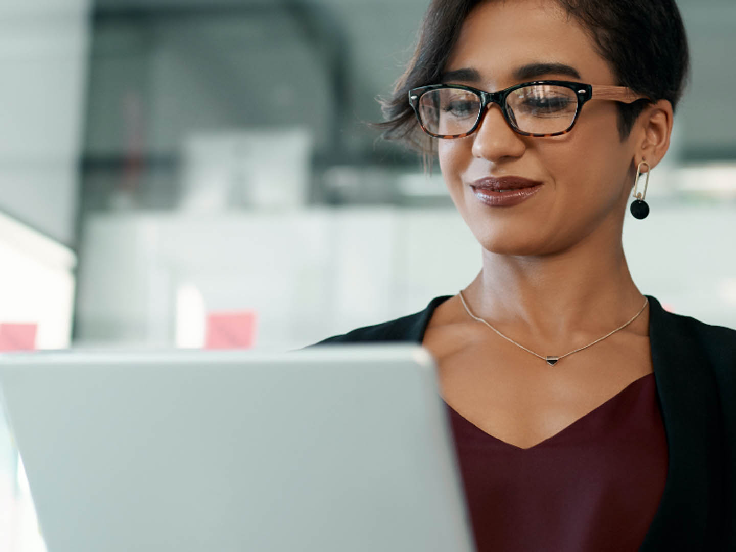 Woman wearing glasses looking at laptop.