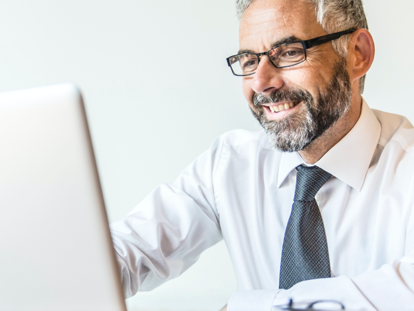 Man wearing glasses looking at laptop computer.