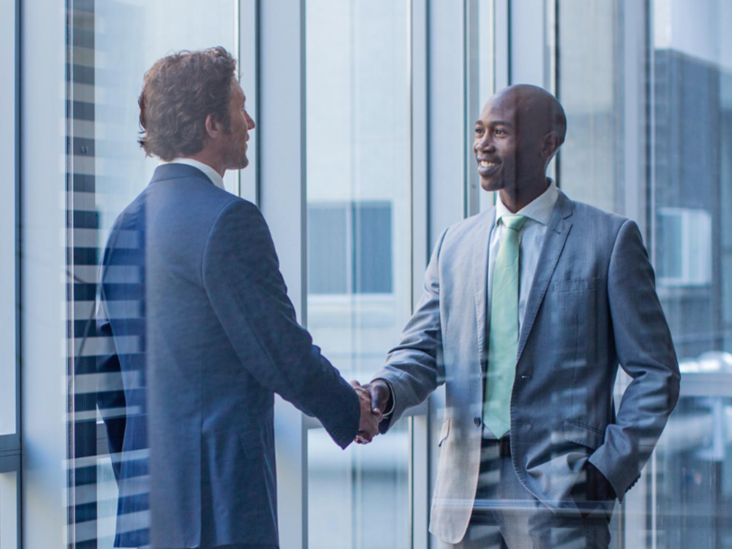 two businessmen shaking hands in office.