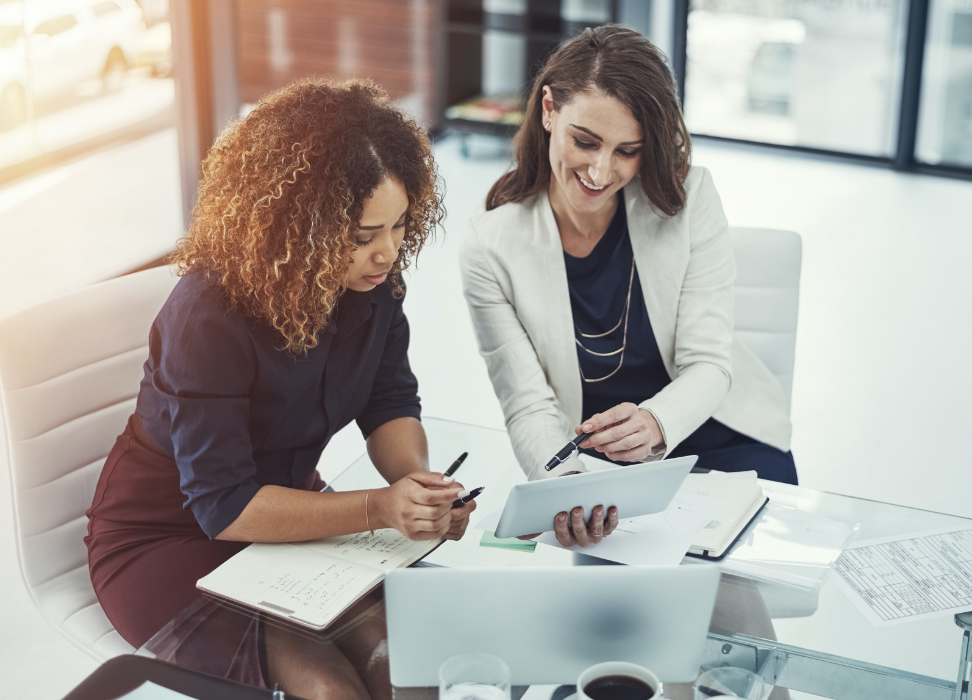 Two women sitting at table reviewing paperwork.