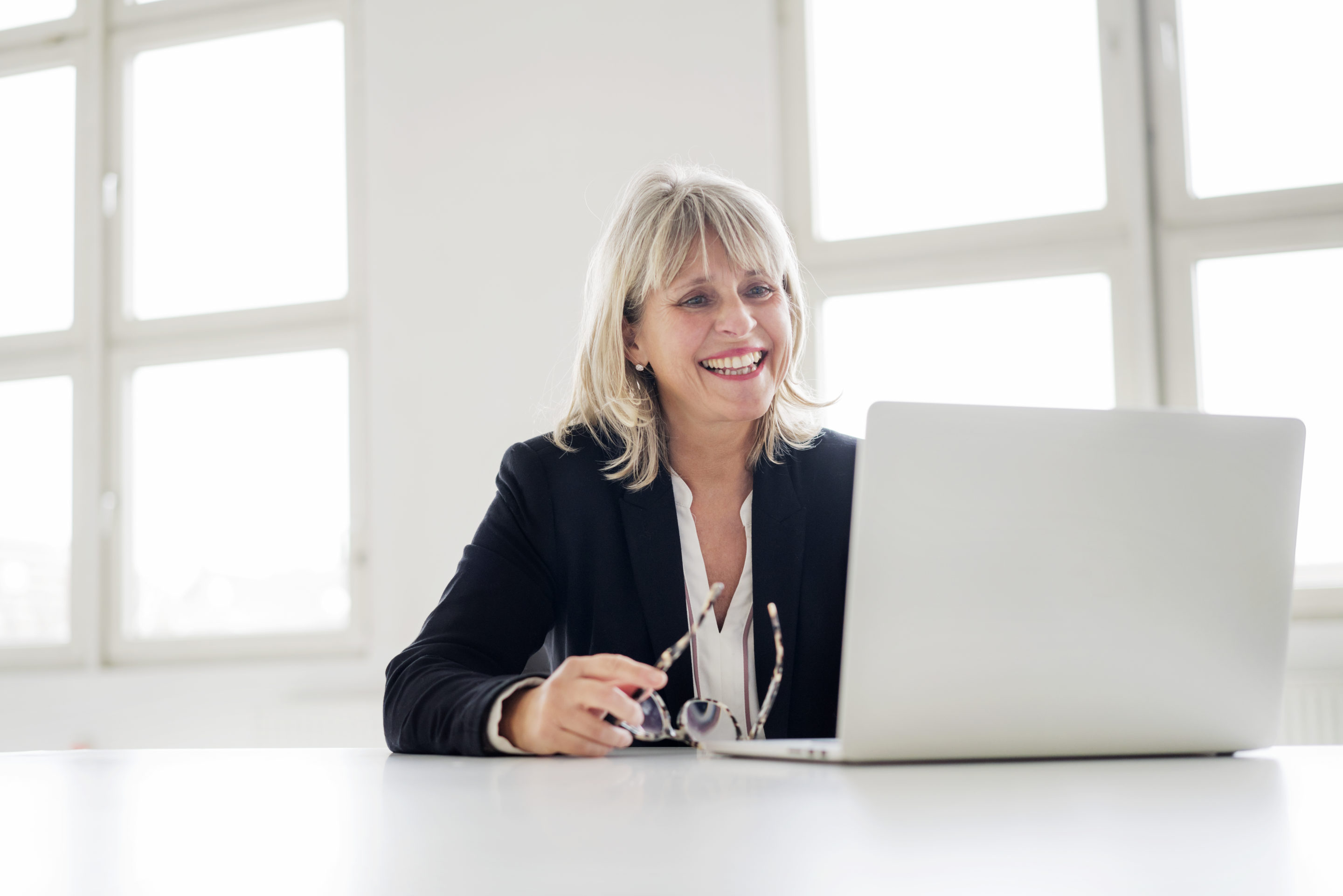 Smiling mature businesswoman working on laptop at desk in the office