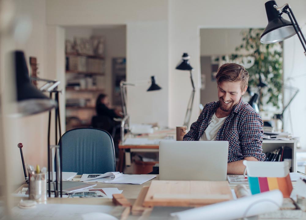 Man siting at desk in office with laptop.