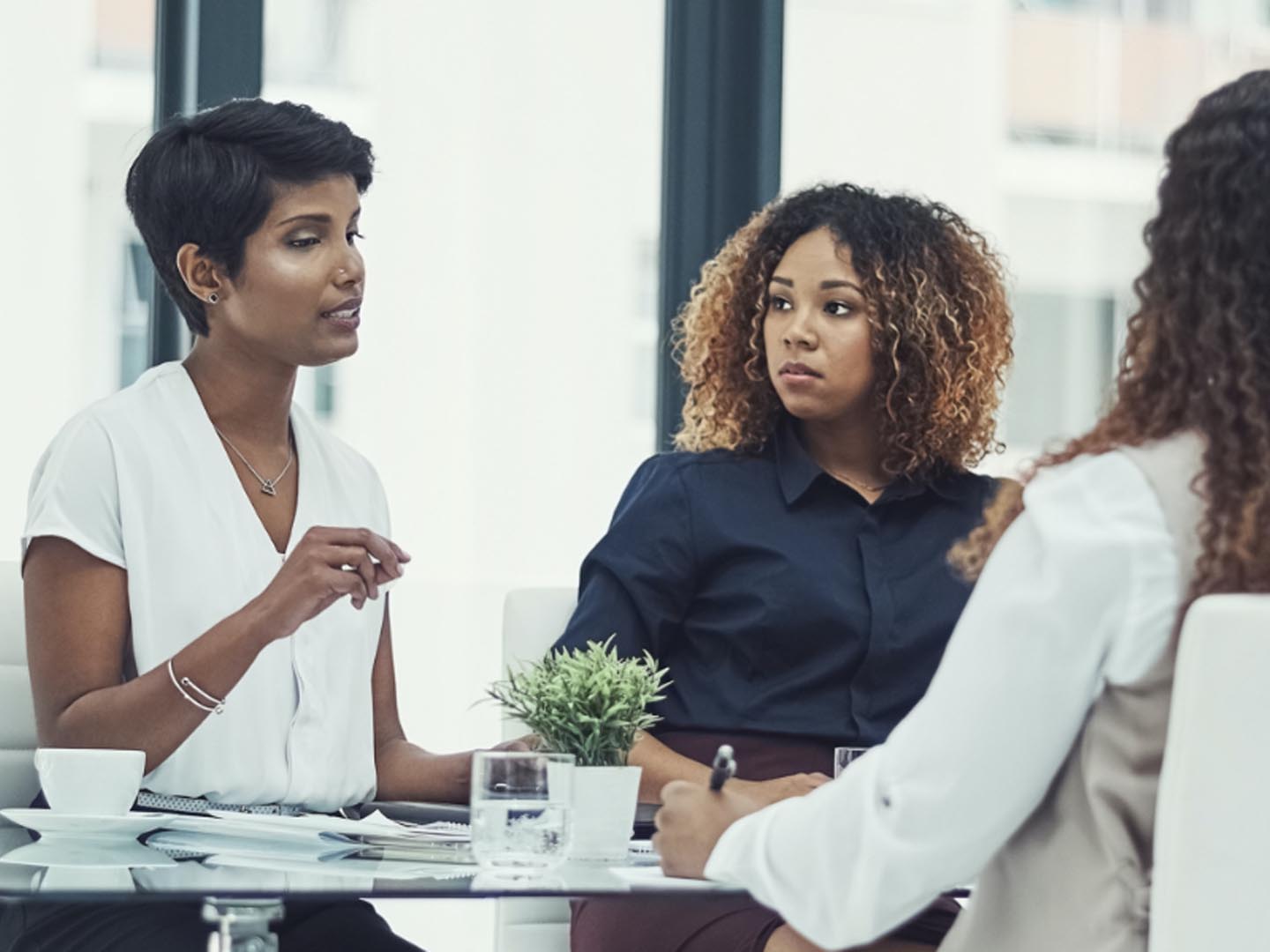 Three women sitting at table talking.