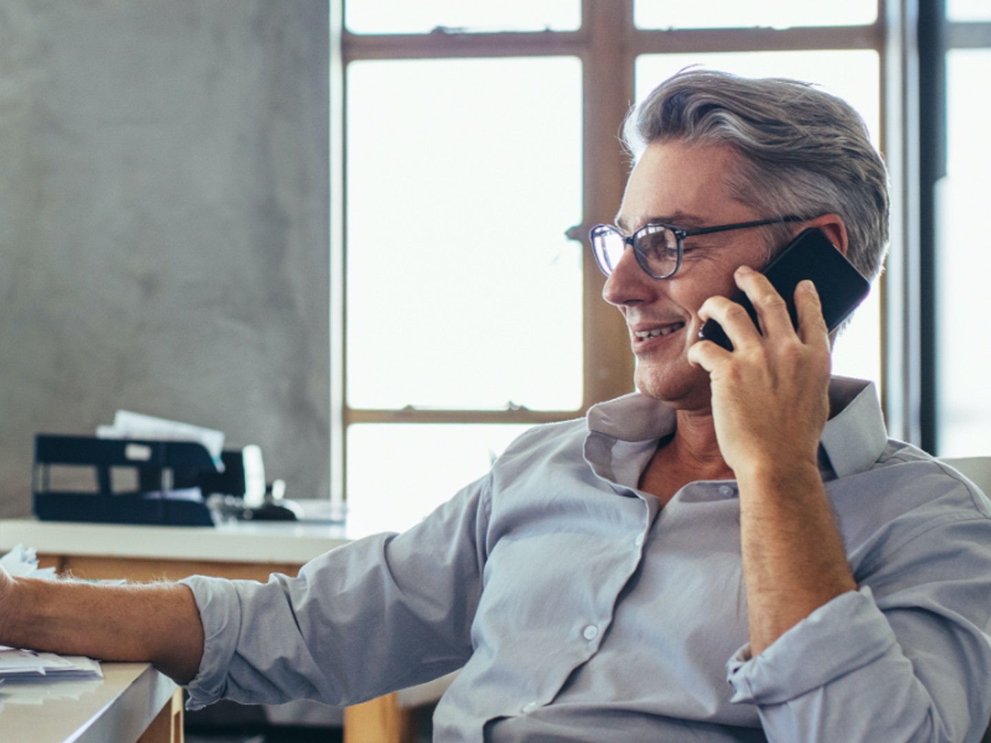 Man sitting at desk talking on mobile phone.