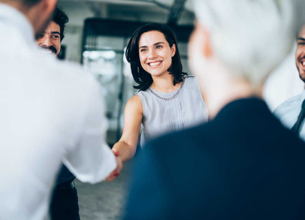 Woman in group setting shaking hands with man.