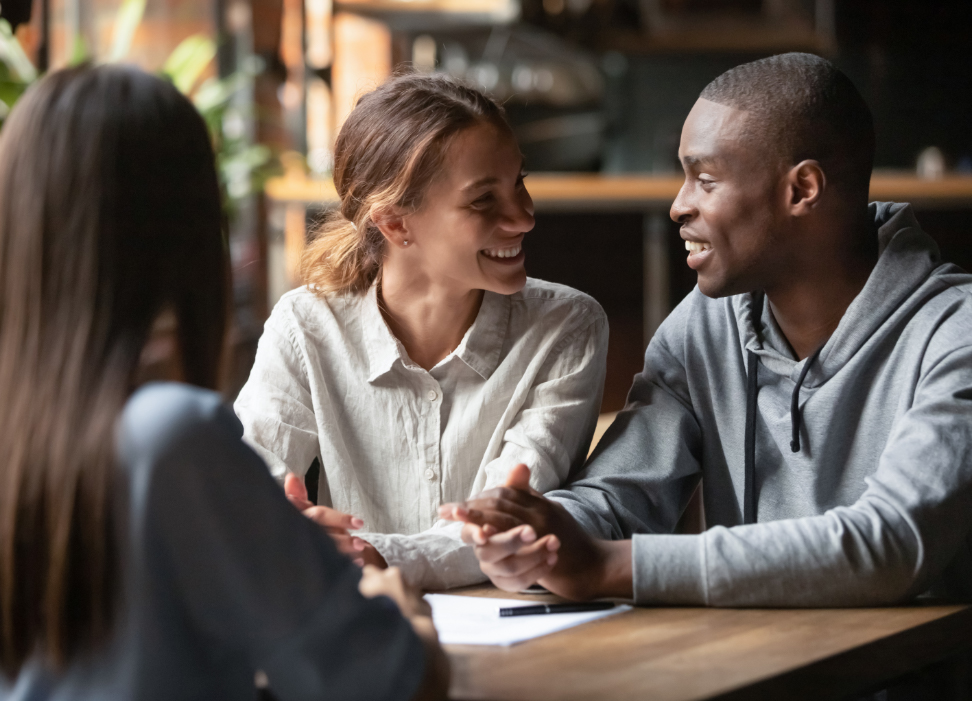 Man and woman sitting at a table smiling at each other.