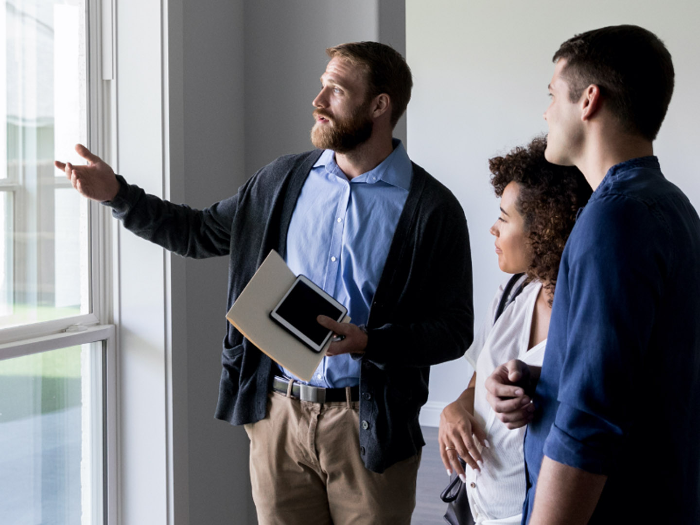 Man speaking with woman and man pointing out of a window.