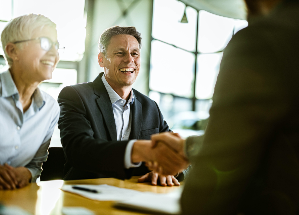 Man and woman sitting at desk shaking hands.