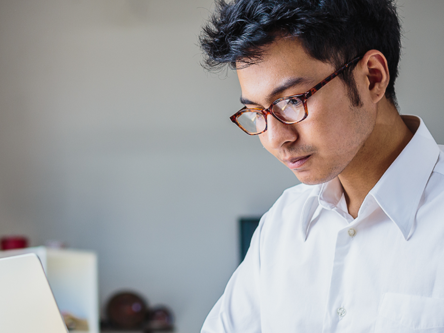 Man wearing glasses looking at laptop.