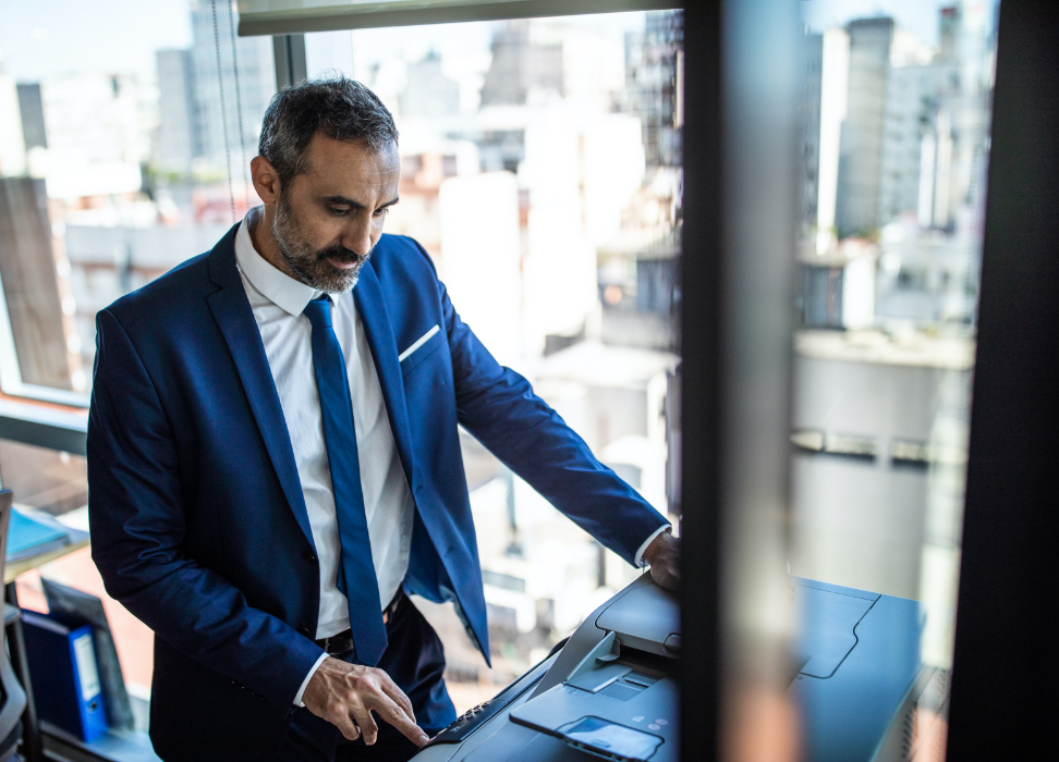 Man standing at desk looking at laptop.