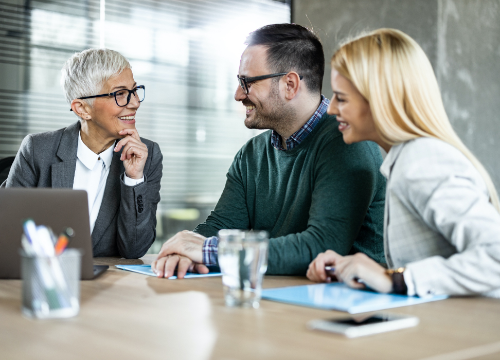 Man and woman sitting at table with mature woman wearing glasses.