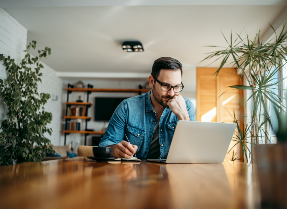 Man wearing glasses sitting at table with laptop.