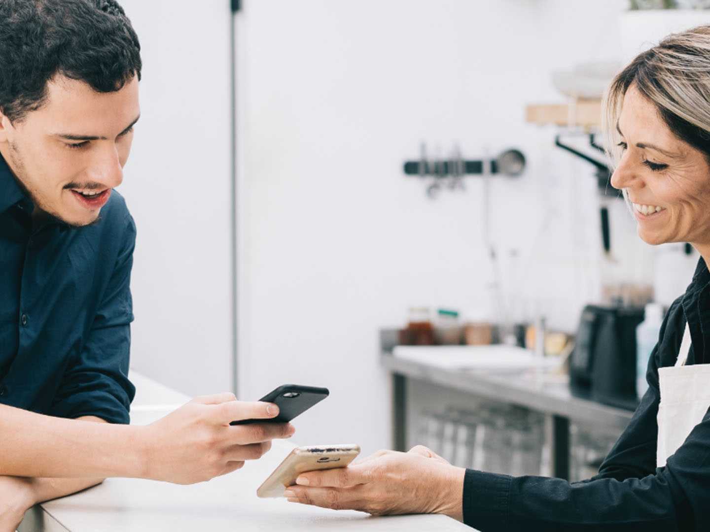 Man and woman at table looking at mobile phones.