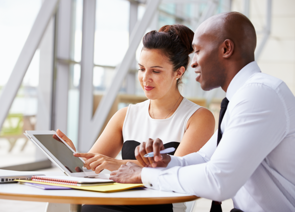 Woman showing man something on tablet.