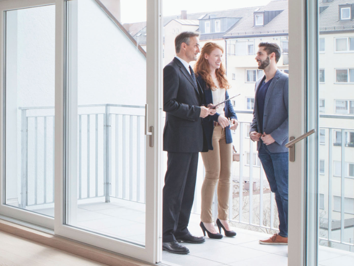 Two men and woman standing on balcony speaking.