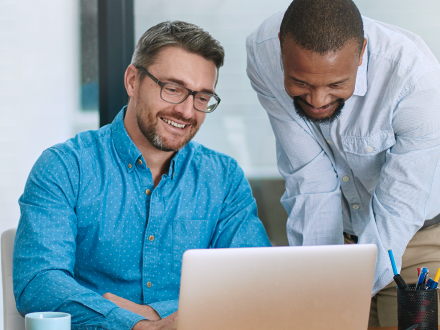 Two men smiling looking at laptop.