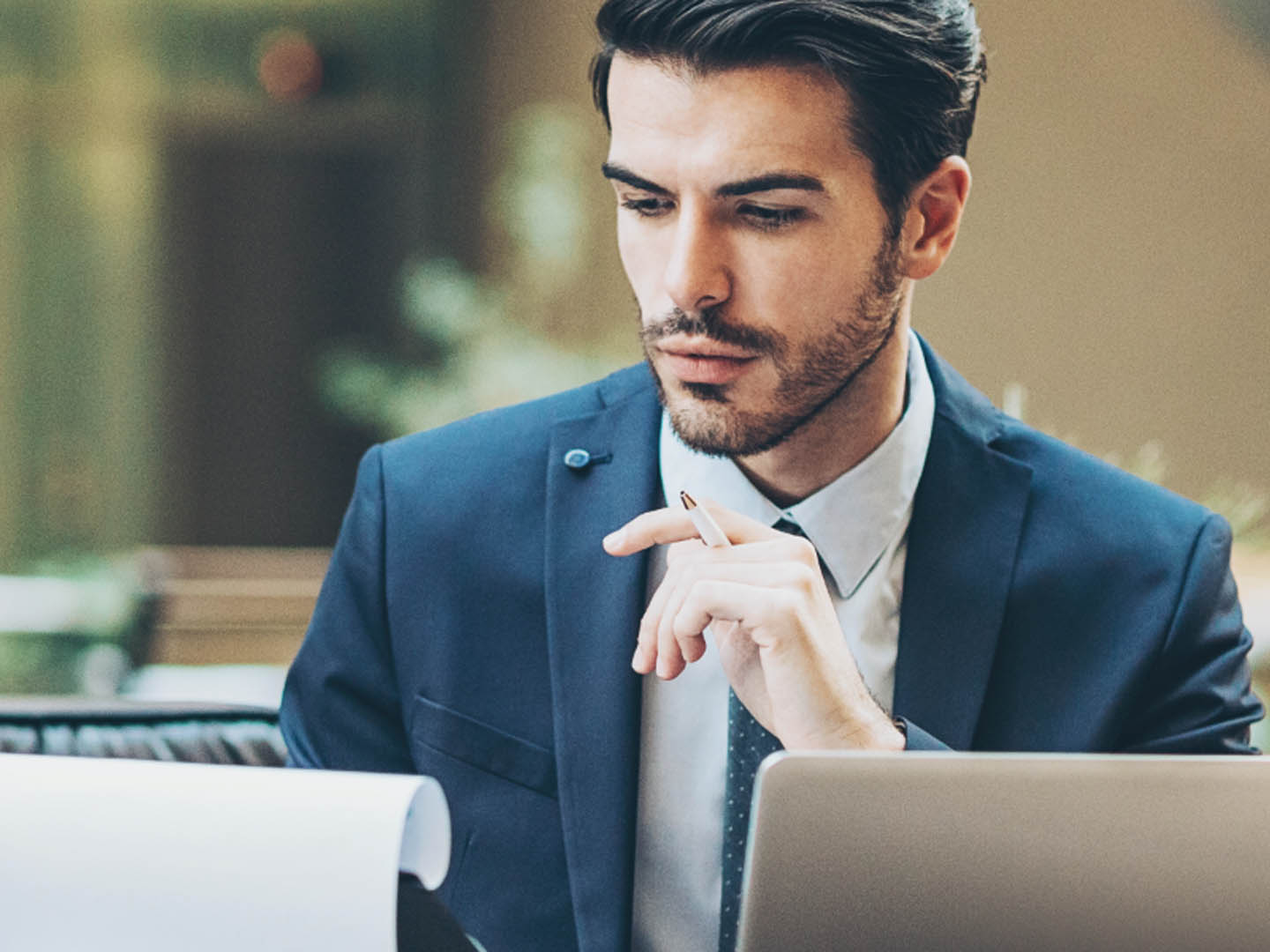 Businessman sitting at desk looking at pad of paper.