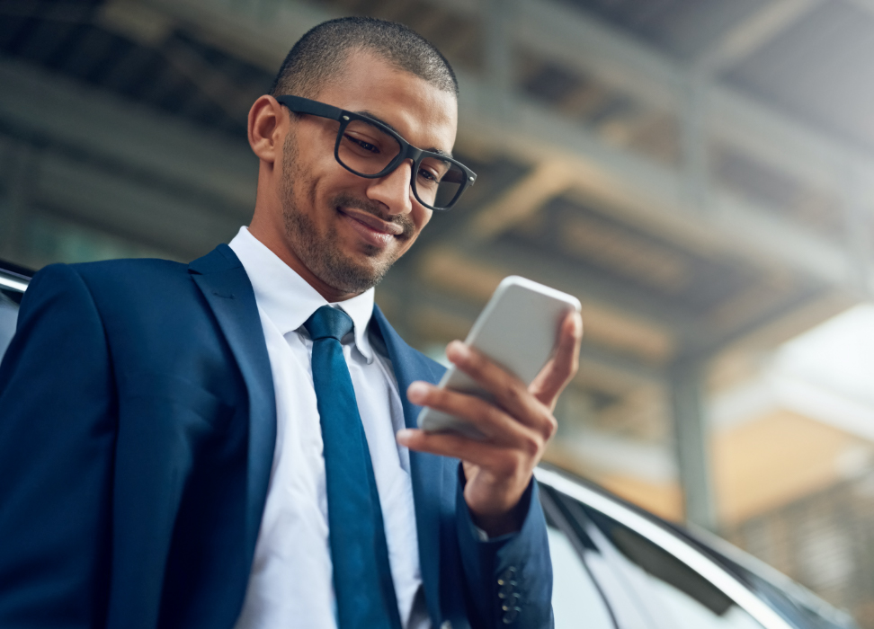 businessman standing outside smiling at mobile phone