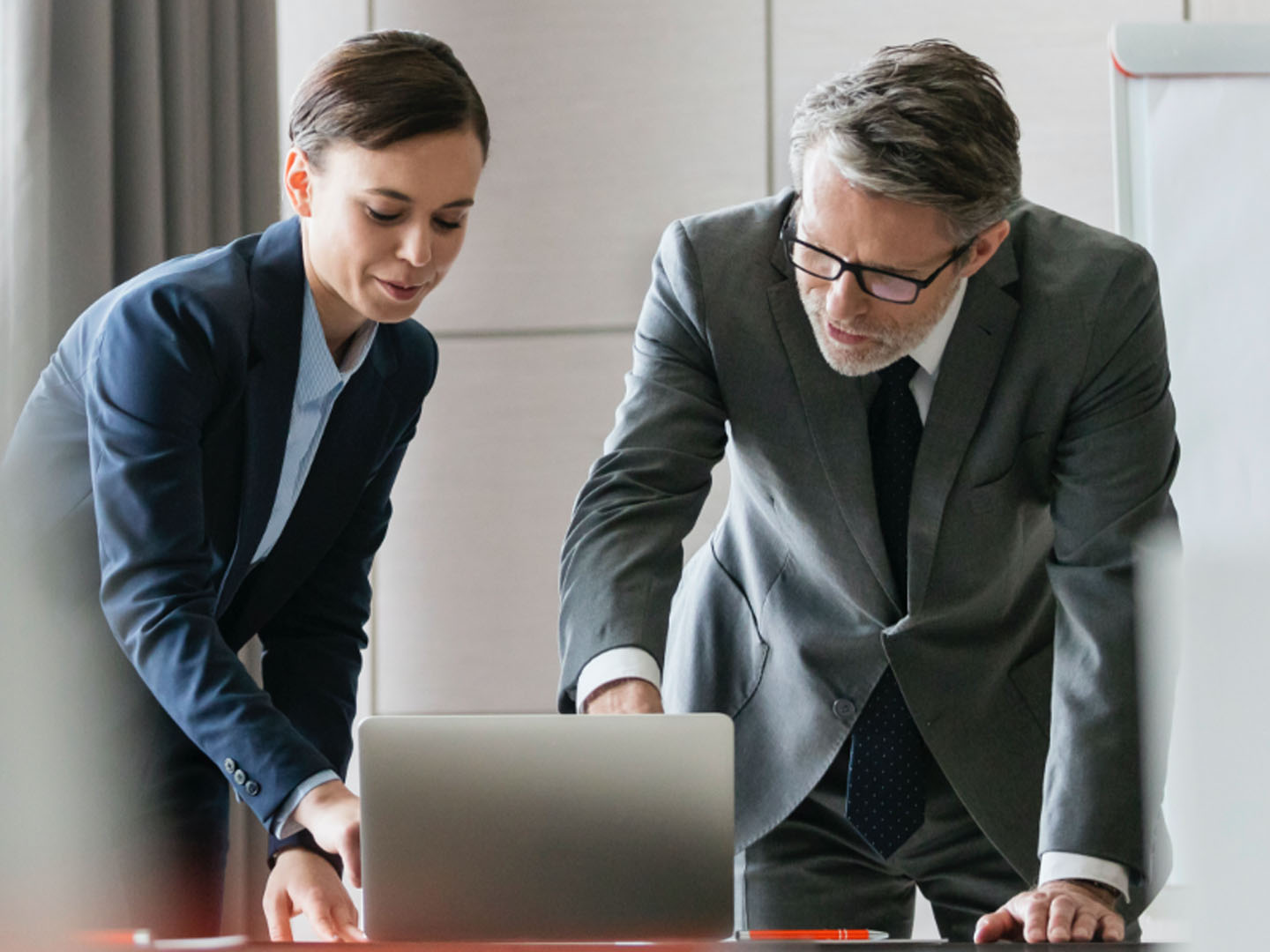 Man and woman in business attire looking at laptop.