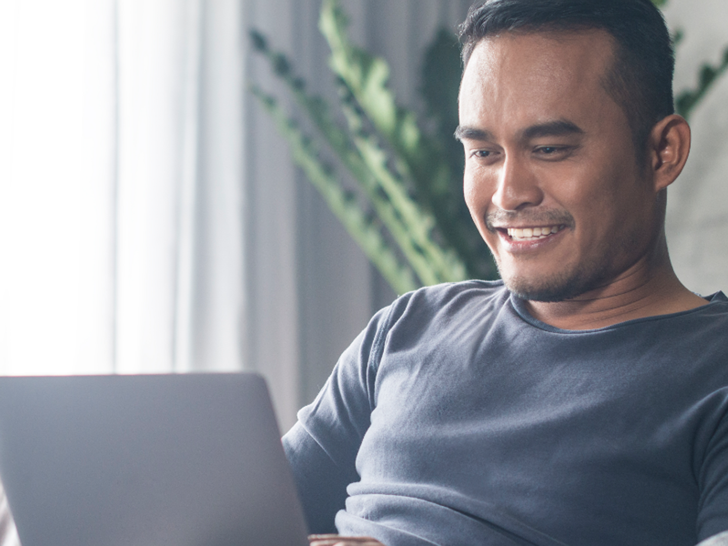 Seated man looking at laptop.