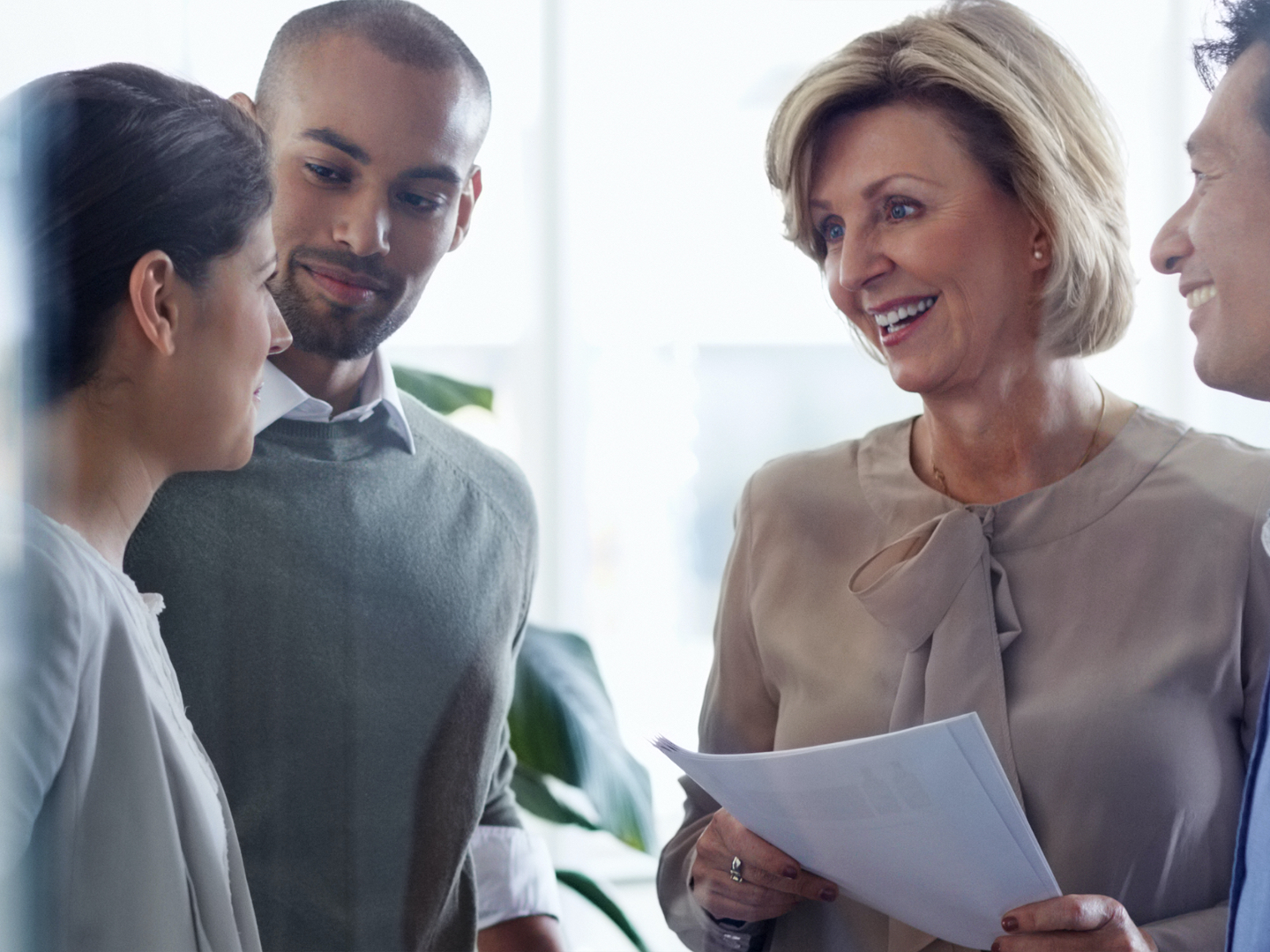 Two women and two men standing in a group at office setting.