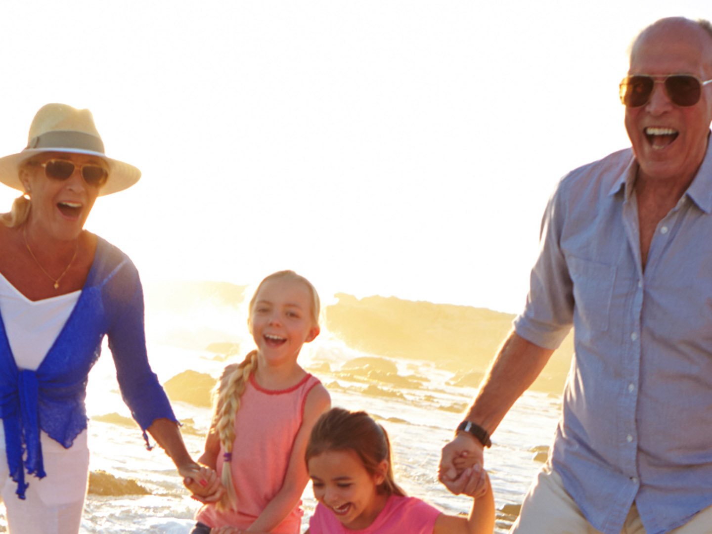 Senior man and woman with two children at the beach.