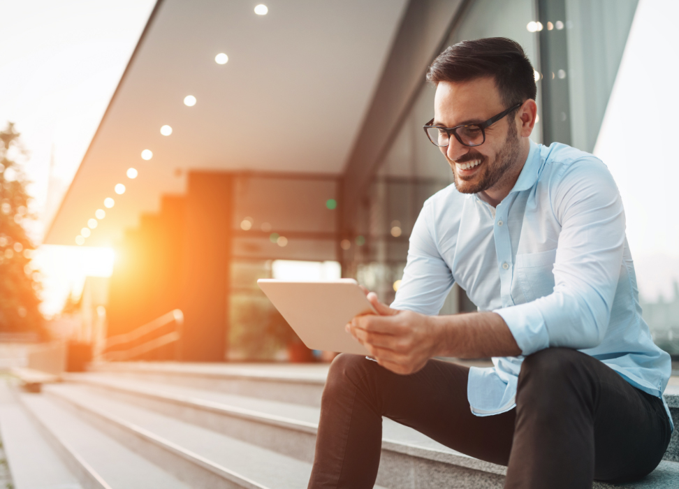 man sitting outside on steps looking at tablet