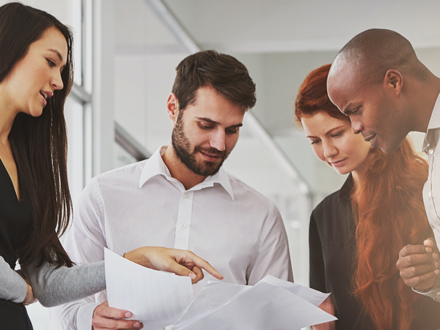 Two men and two woman standing together looking at paperwork.