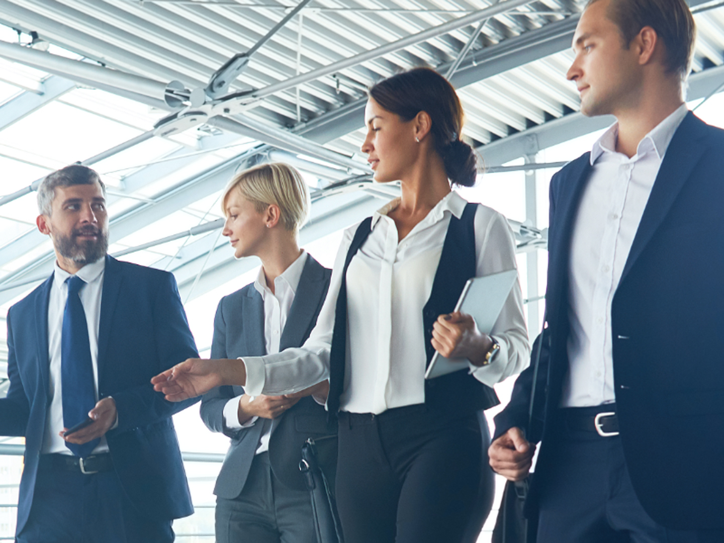 Two men and two women in business attire walking and talking.