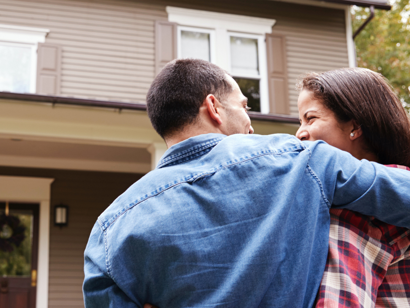 Man and woman smiling at each other faced away from camera walking toward house.