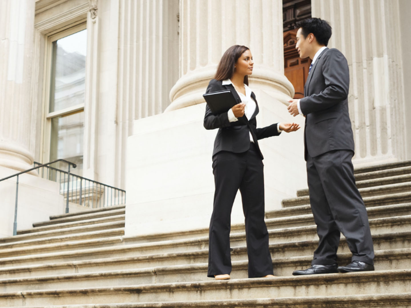 Businesswoman and businessman speaking on steps.