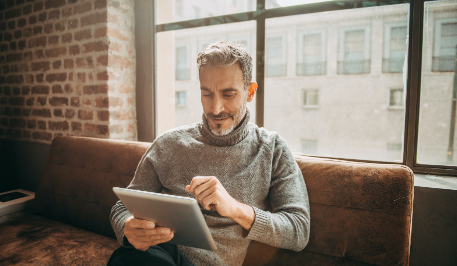 Man sitting on couch looking at tablet