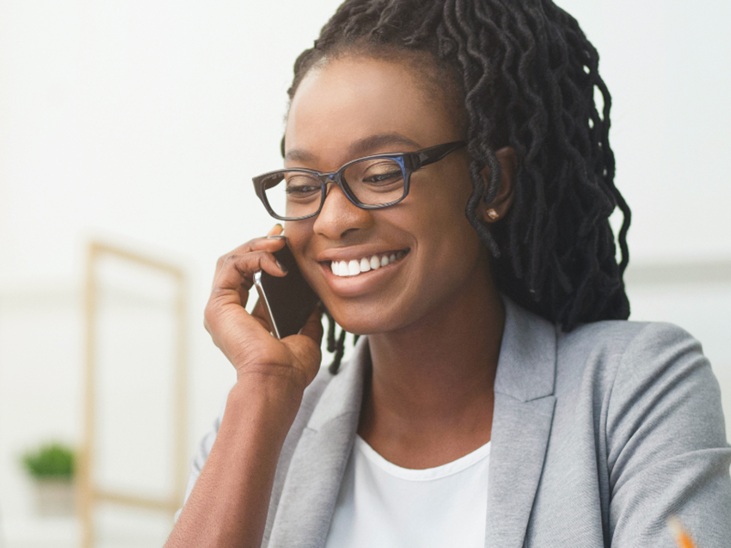 Woman wearing glasses smiling holding mobile phone.