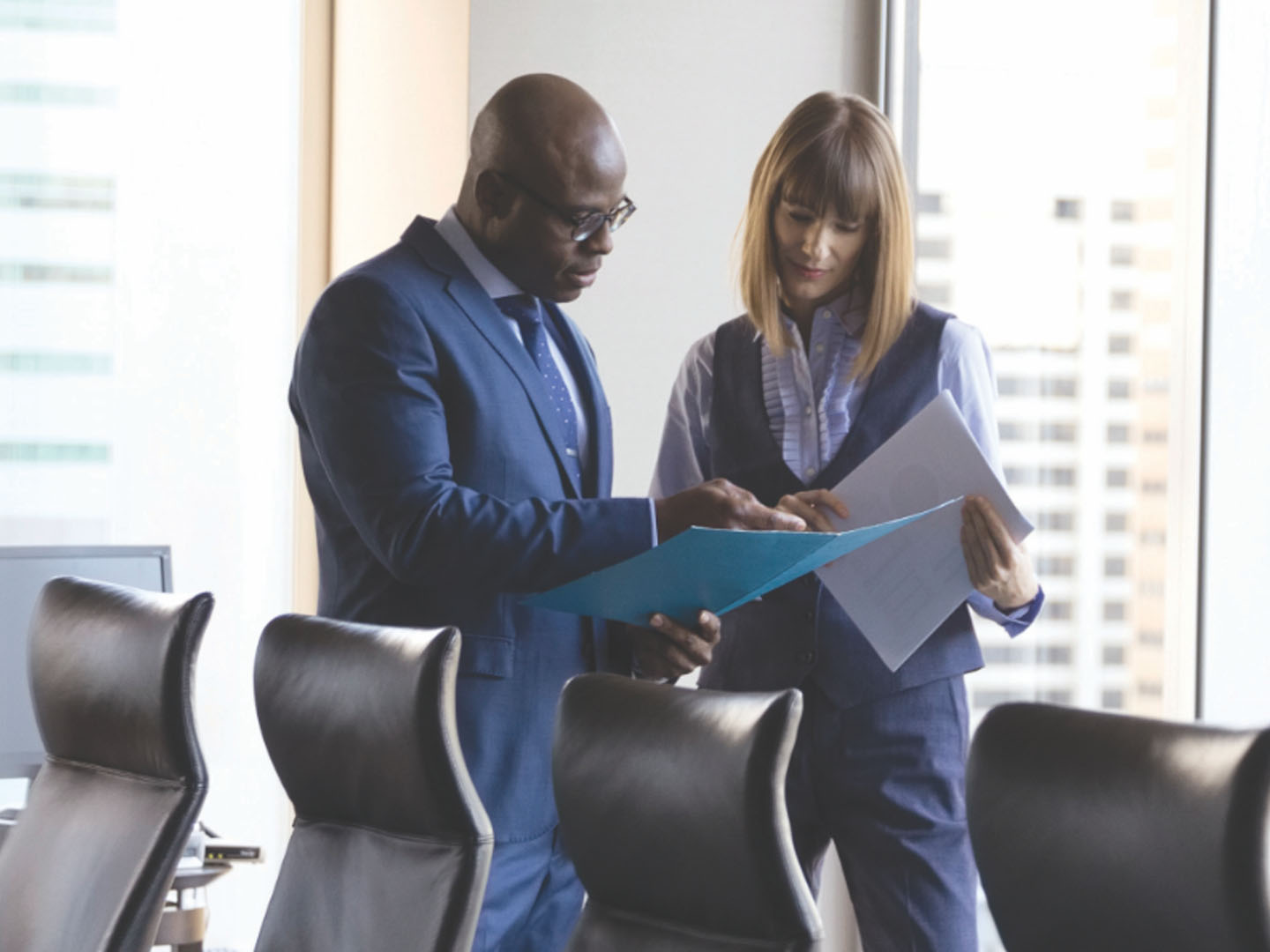 Business man holding folder speaking to woman holding paper