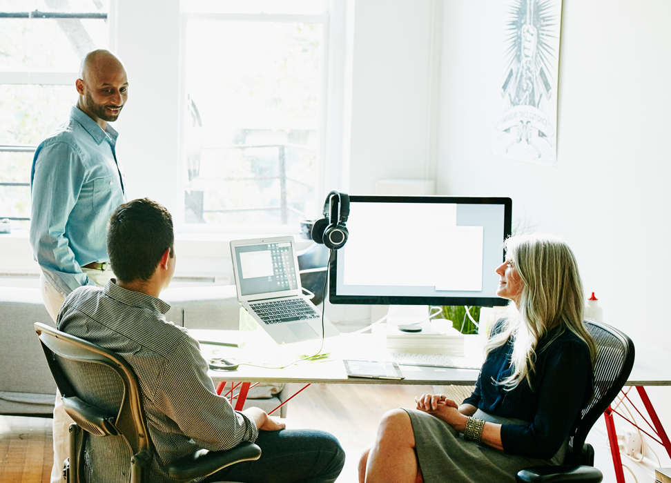 Two men and a woman talking in office