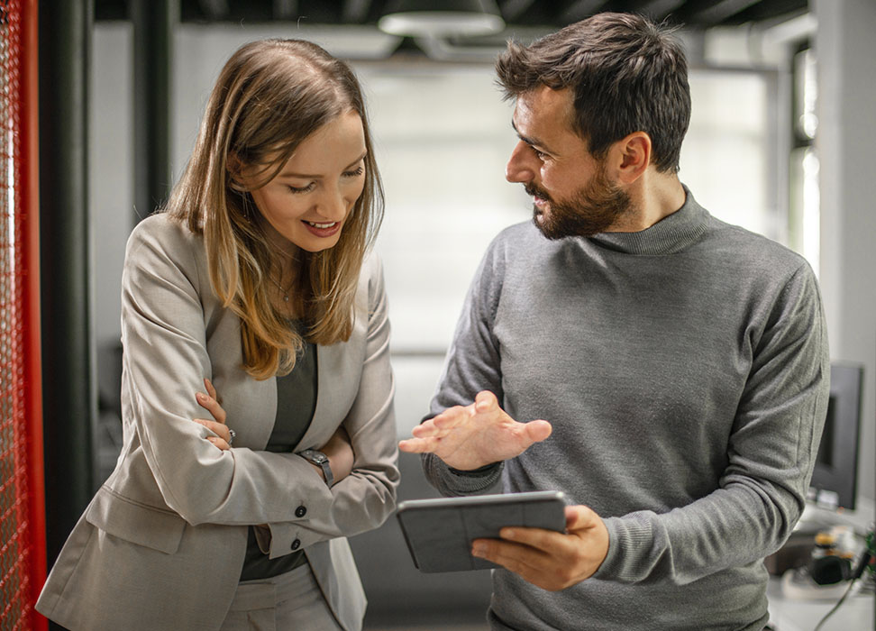 Business man holding tablet talking to business woman
