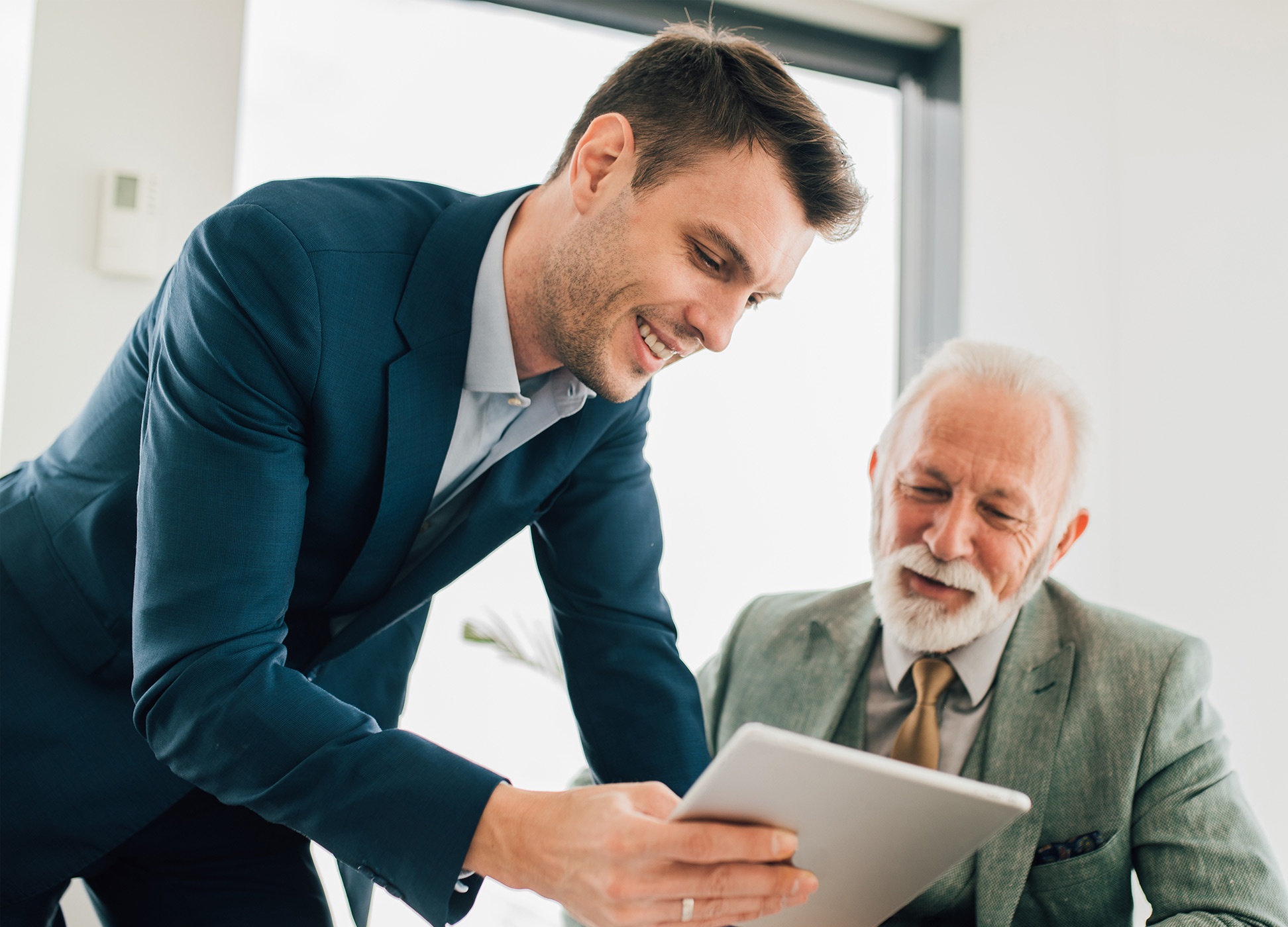 two businessmen using a tablet in an office