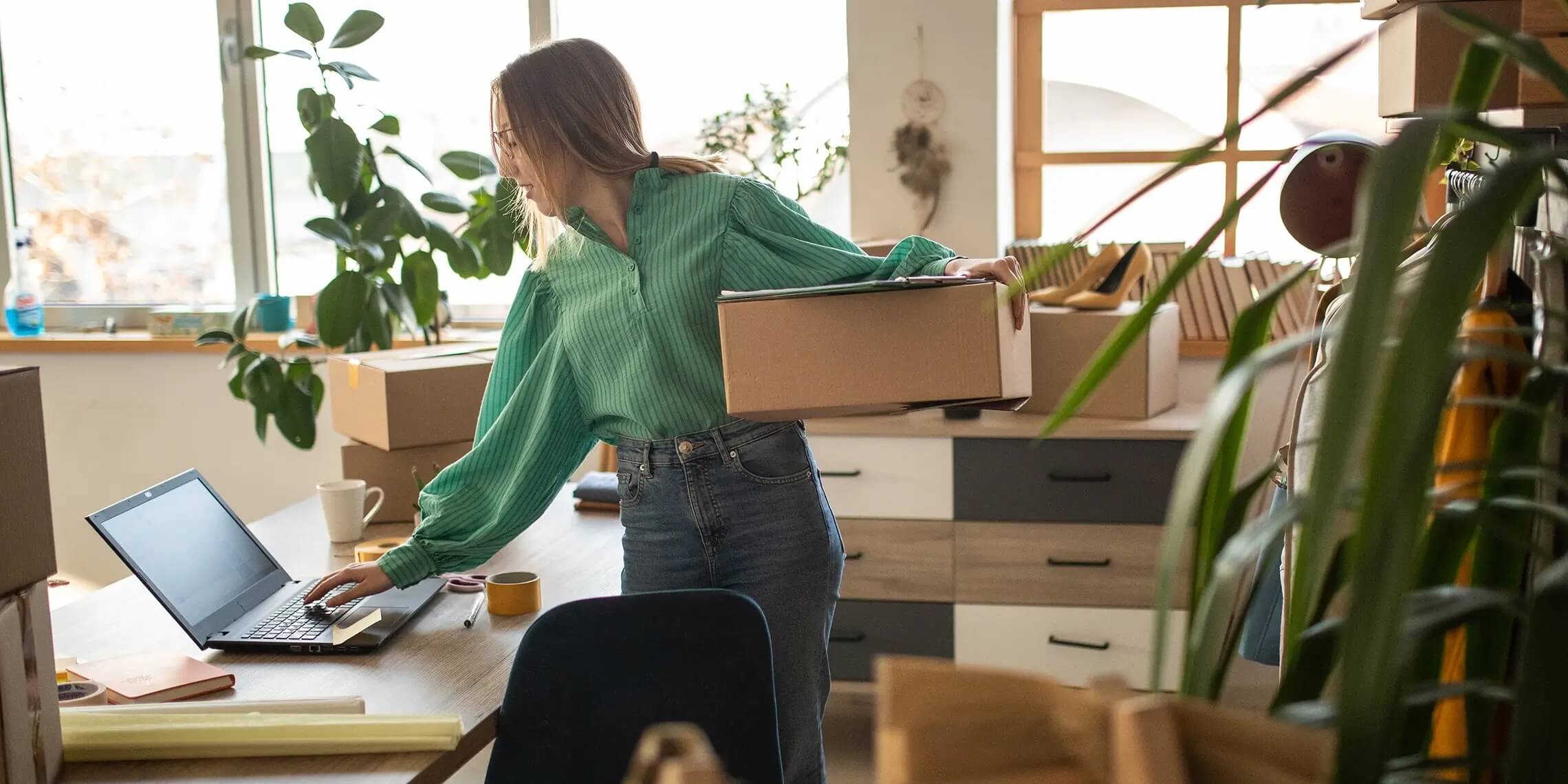 Woman business owner using prepping packages on laptop