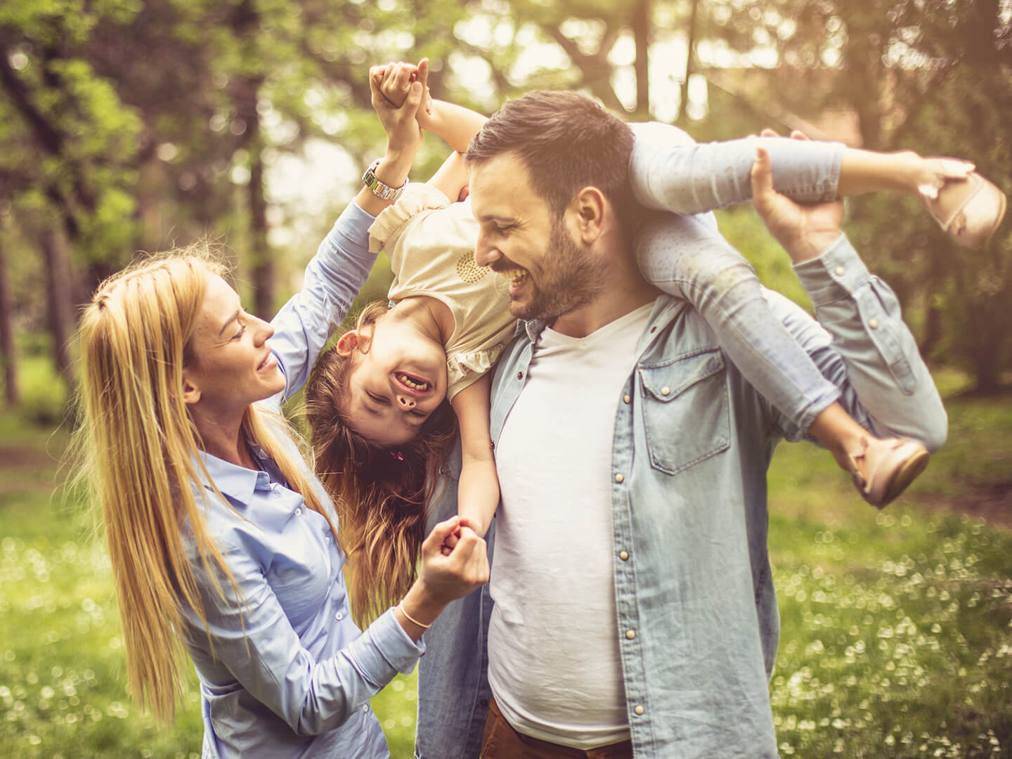 husband and wife playing with child outside in the woods