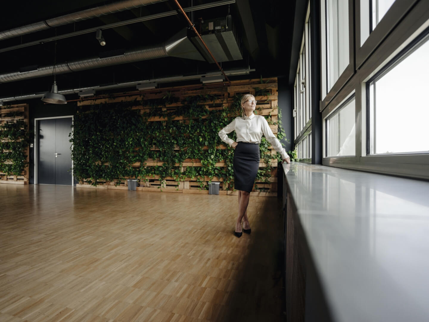 business woman in open office space looking out window