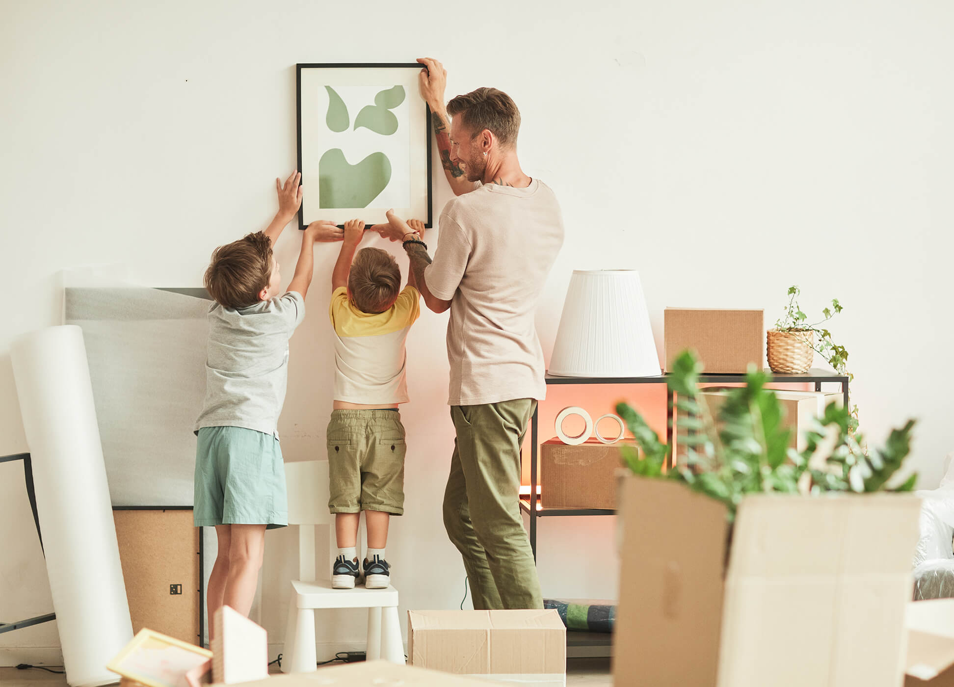 father and kids hanging picture in new home