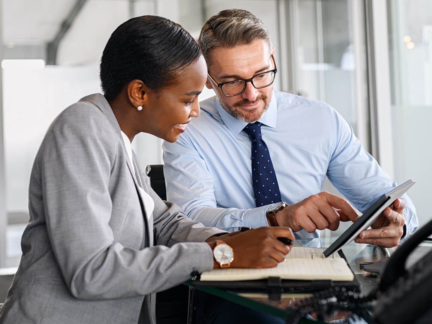 business man and woman looking at checking account options on tablet