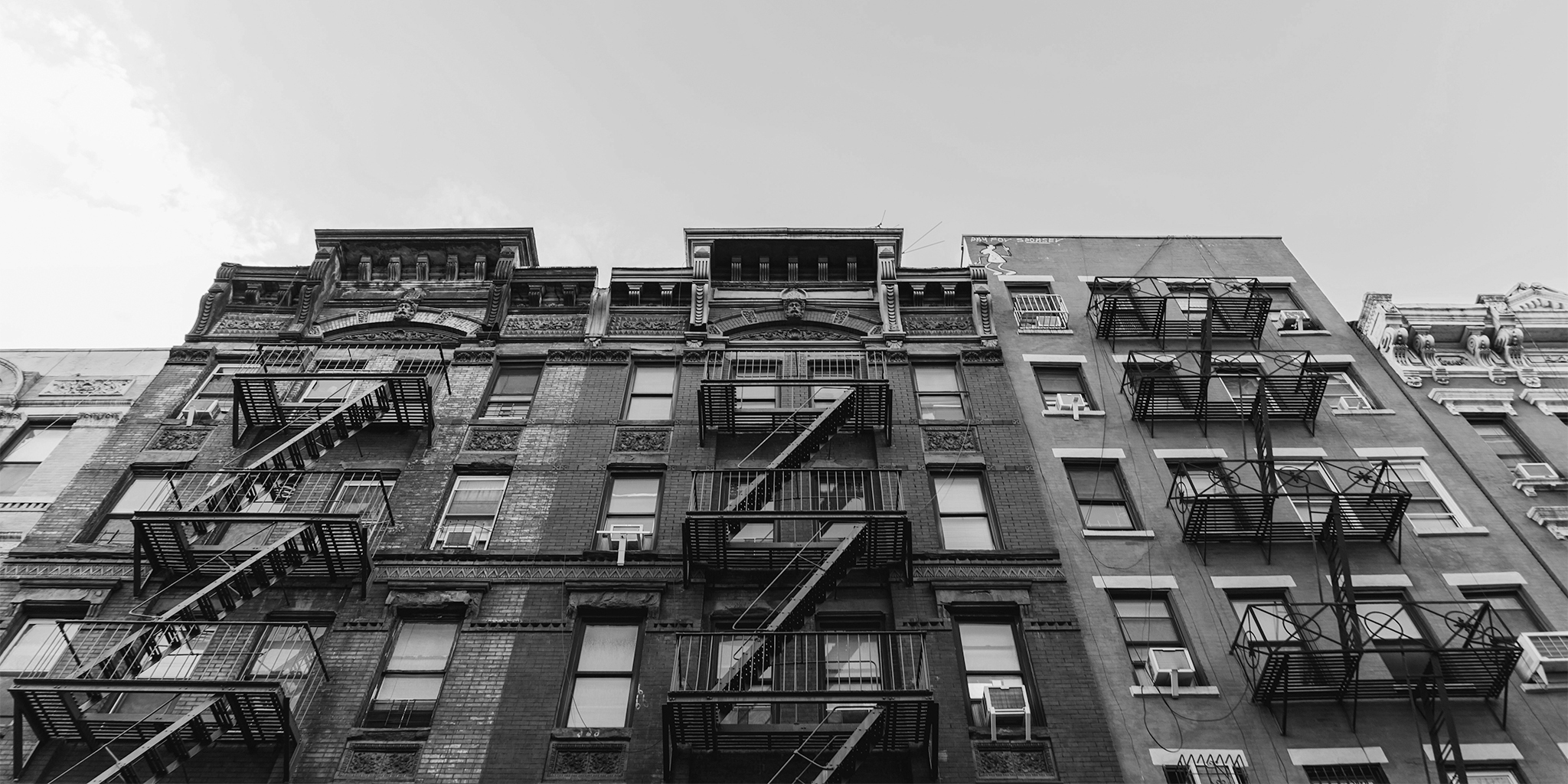 upward view showing a buiding with multiple fire escapes stairs in grayscale